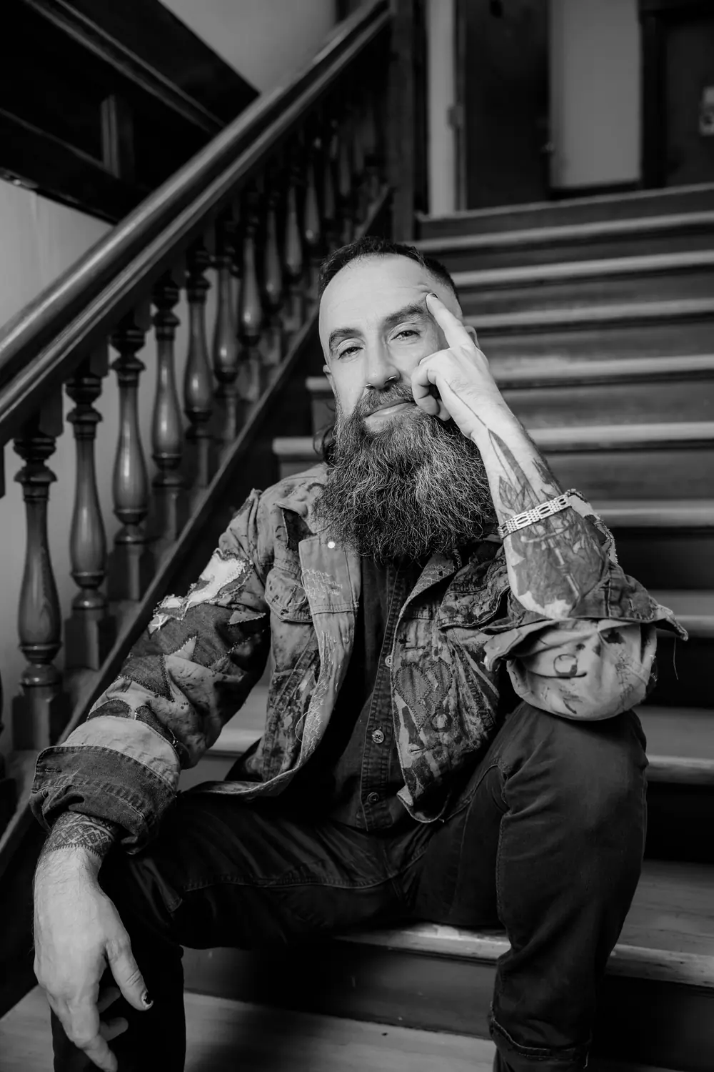 Kris Krüg sitting on stairs, finger at his temple. Photograph by Michelle Diamond.